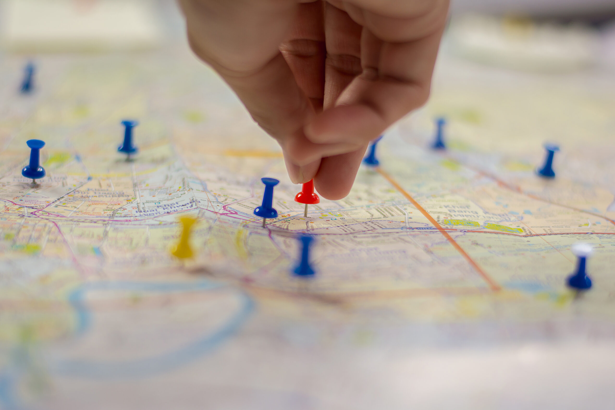 Hand pinning a push pin on a map as a target